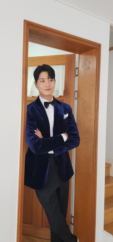 네이비 벨벳 재킷을 입고 문가에 선 신랑